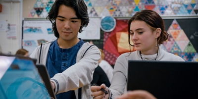 Dos estudiantes haciendo tareas juntos en laptops